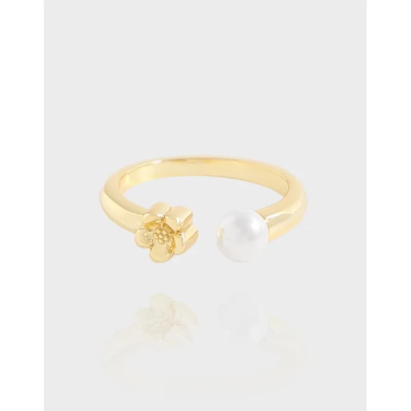 Gold-tone ring with a floral end on one side and a pearl end on the other