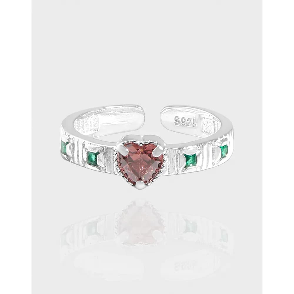 Polished sterling silver ring with a pink heart-shaped center stone and green accent stones on the band.