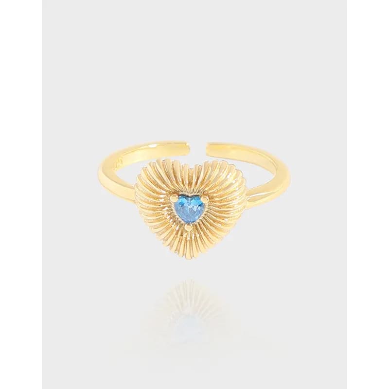 Open, adjustable ring with a sunburst heart centerpiece and a blue heart gem at the center.