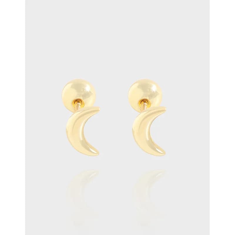 Polished crescent drop earrings with round studs worn on ears.