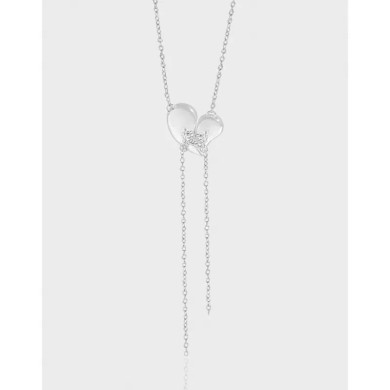 Polished sterling silver necklace with two connected hearts and dangling drop chains on a light background.
