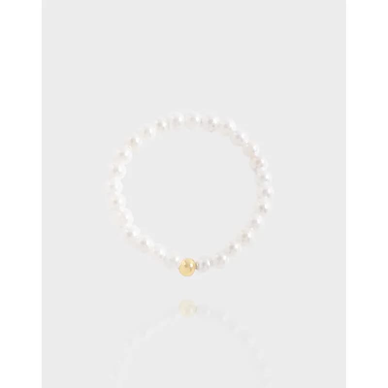 Polished sterling silver ring with beaded white pearls and a small gold disk accent.