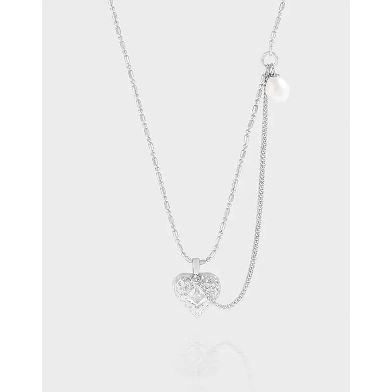 Polished sterling silver heart filigree pendant on a double-chain necklace with a small pearl charm.
