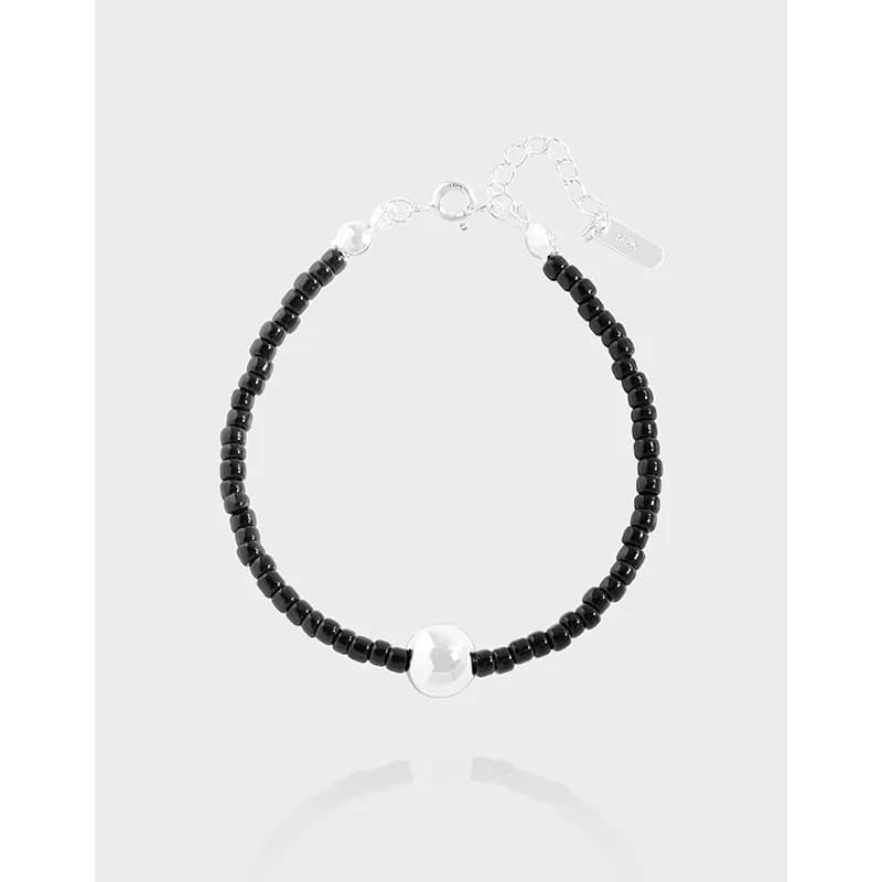 Sterling silver and black beaded bracelet with a prominent central silver bead on a light background.