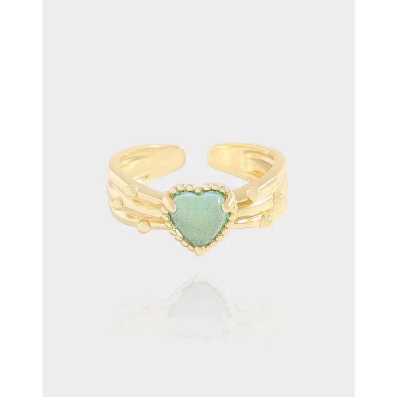Ring with a heart-shaped green stone set in a three-band gold-tone shank with beaded bezel and small heart accents.