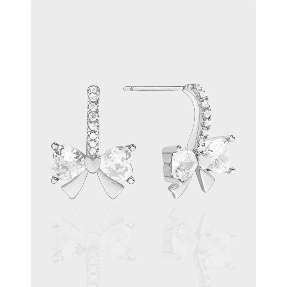 Silver bow-themed drop earrings with pavé crystals and a heart detail at the bow