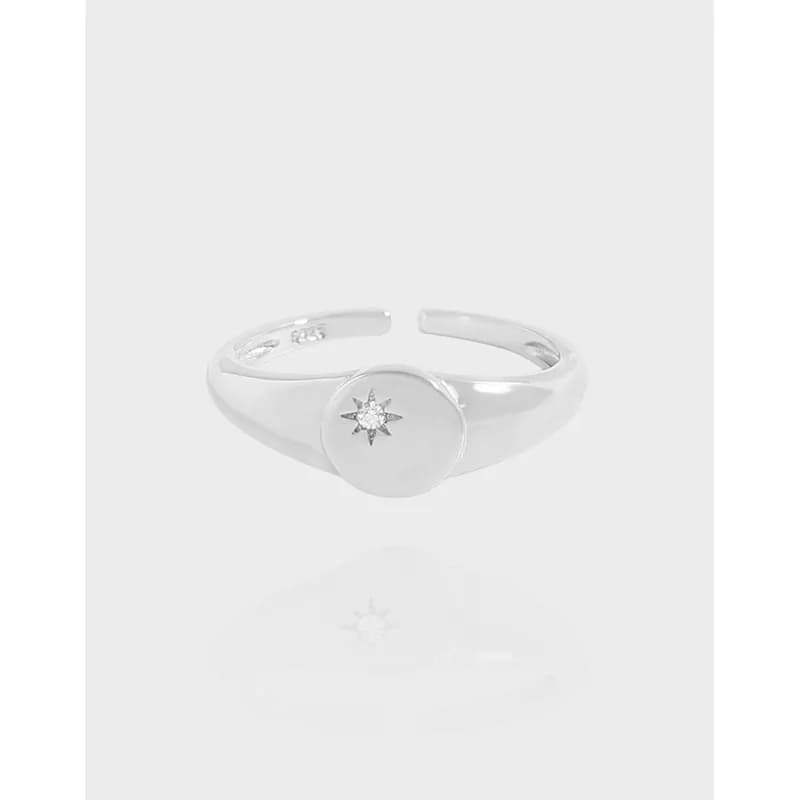 Polished sterling silver ring with a round bezel featuring a starburst diamond cluster