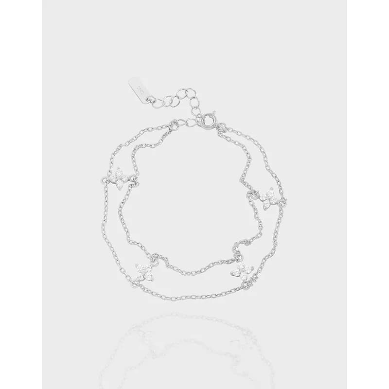 Polished sterling silver double-chain bracelet with small flower stations and a lobster clasp.