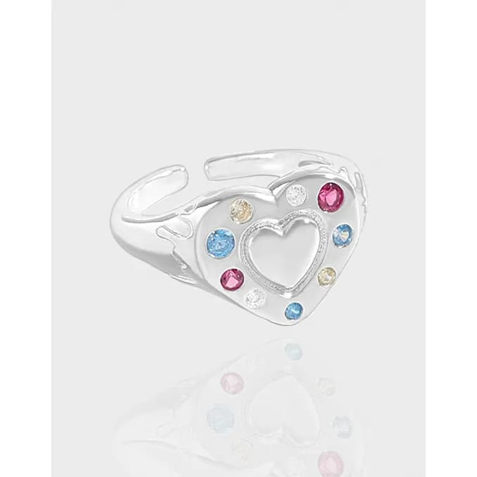Polished silver ring with an open heart cutout and colorful stones around it.