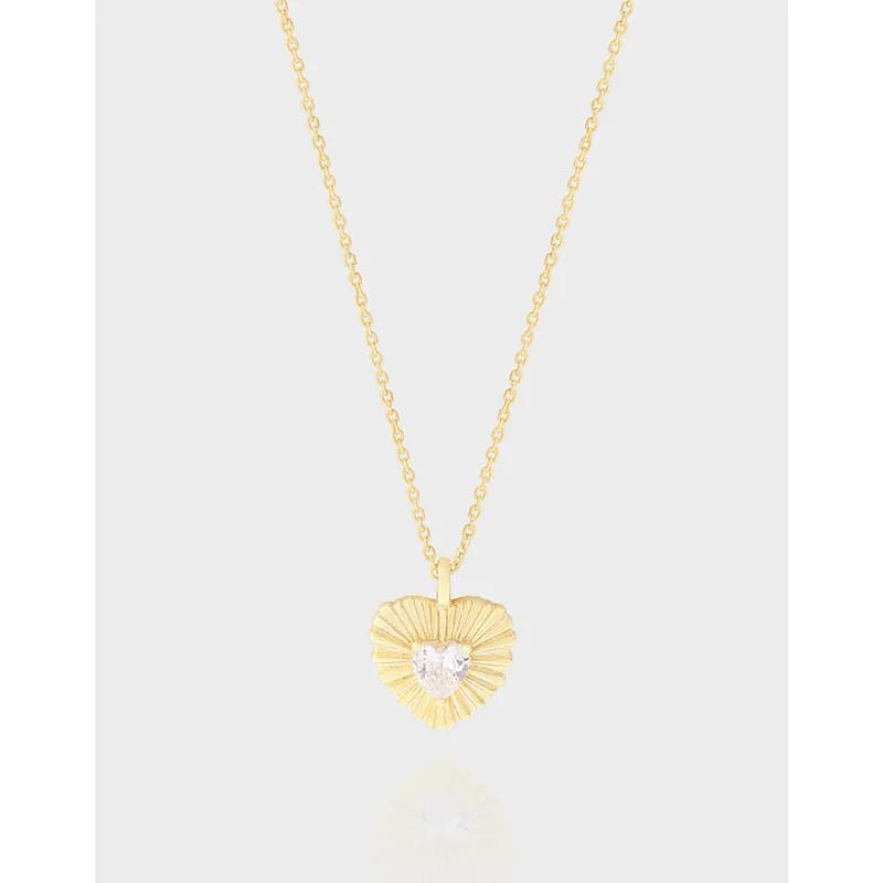 Gold-toned heart pendant with sunburst rays and a clear center stone on a fine chain