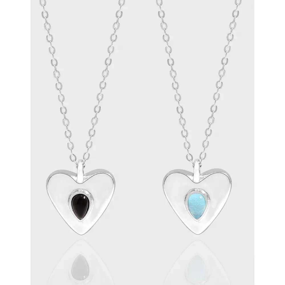 Two silver heart pendants on matching chains, each with a small inset gemstone in the center.