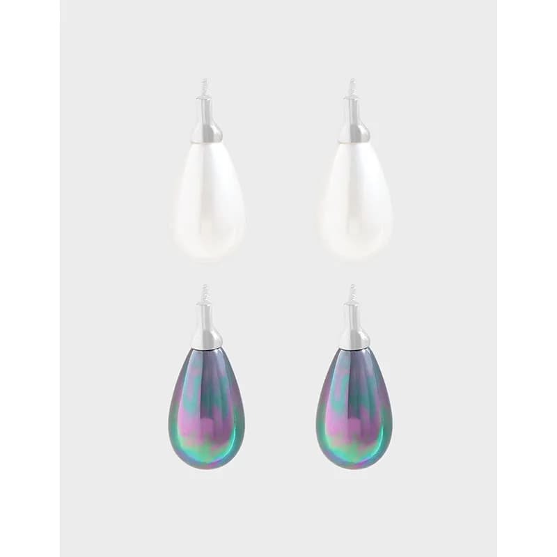 Two teardrop earrings in white pearl and iridescent purple-green shell hanging from silver posts.