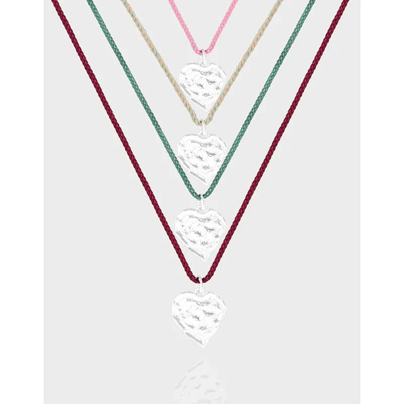 Layered silver heart pendants on multiple colored cords arranged in a tiered necklace display.