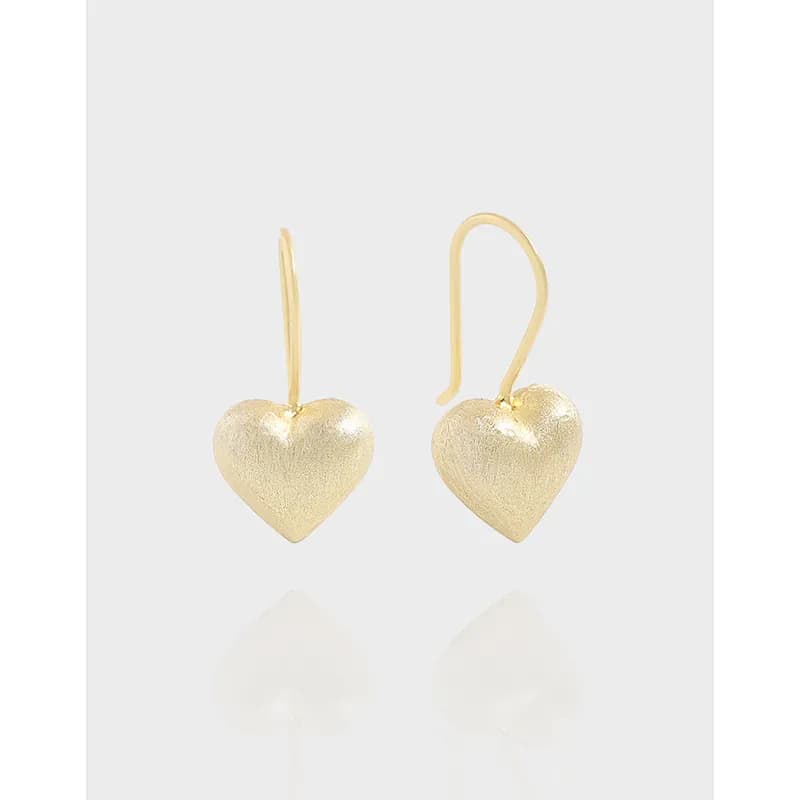 Polished sterling silver heart drop earrings with curved hooks on a light background.