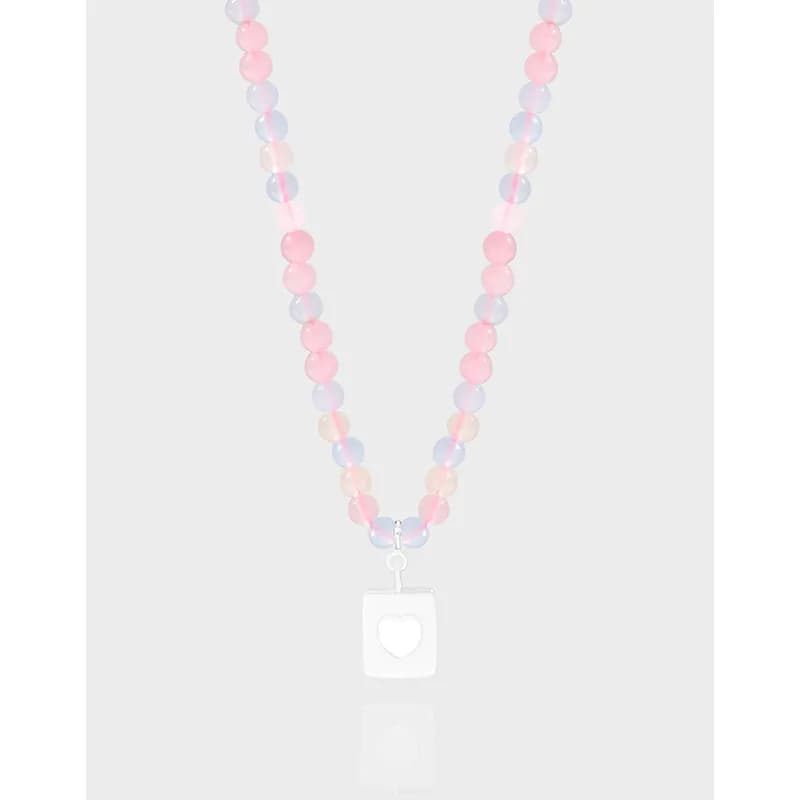 Pastel bead necklace with square heart pendant on a light background.