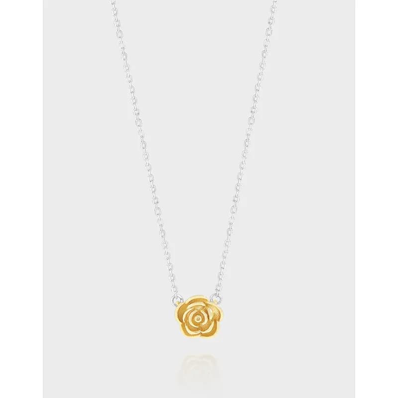 Delicate silver chain necklace with a small gold rose pendant against a light grey background.