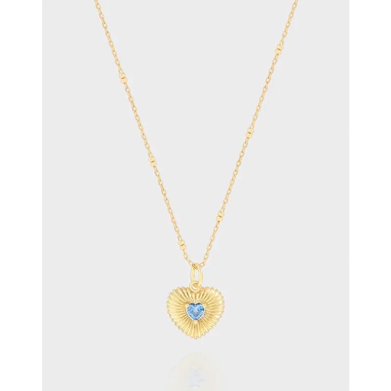 Heart-shaped sunburst pendant with a blue center stone on a delicate chain