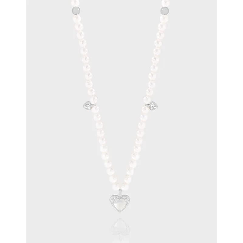 Pearl bead necklace with a silver heart pendant and two crystal-heart charms on the chain.