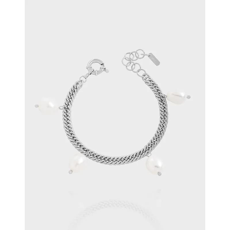 Polished sterling silver curb chain bracelet with pearl drops and adjustable extender on a neutral background.