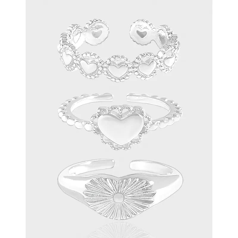 Three sterling silver rings with heart motifs and beaded halos stacked in a vertical arrangement on a light background.