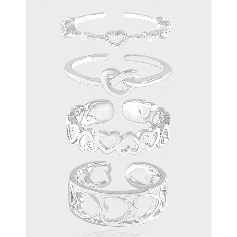 Vertical collage of five sterling silver rings with heart motifs and cutout designs