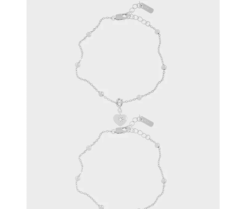 Two delicate sterling silver charm bracelets with heart and star pendants on a plain background.