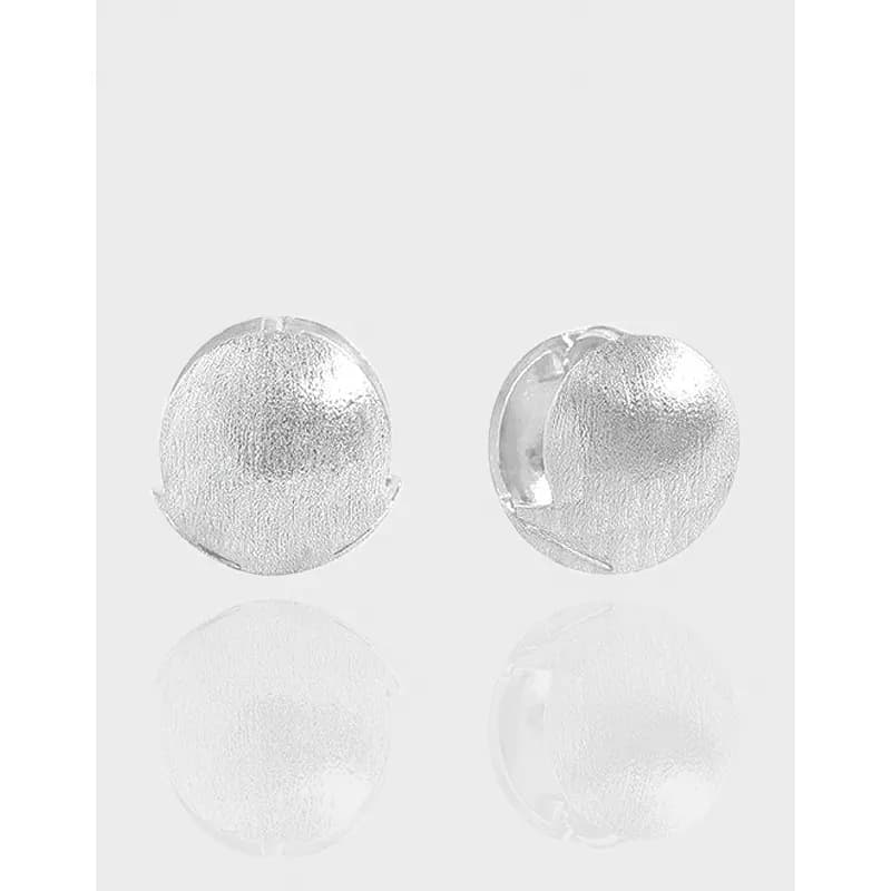 Pair of textured round disc sterling silver stud earrings with polished surfaces.