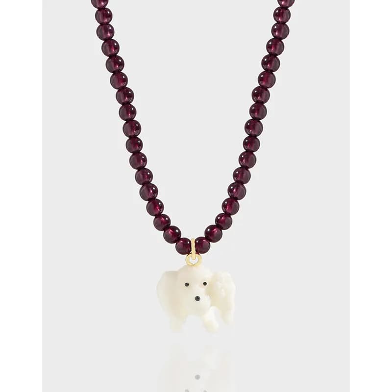 Polished burgundy bead necklace with ivory poodle pendant on a gold bail