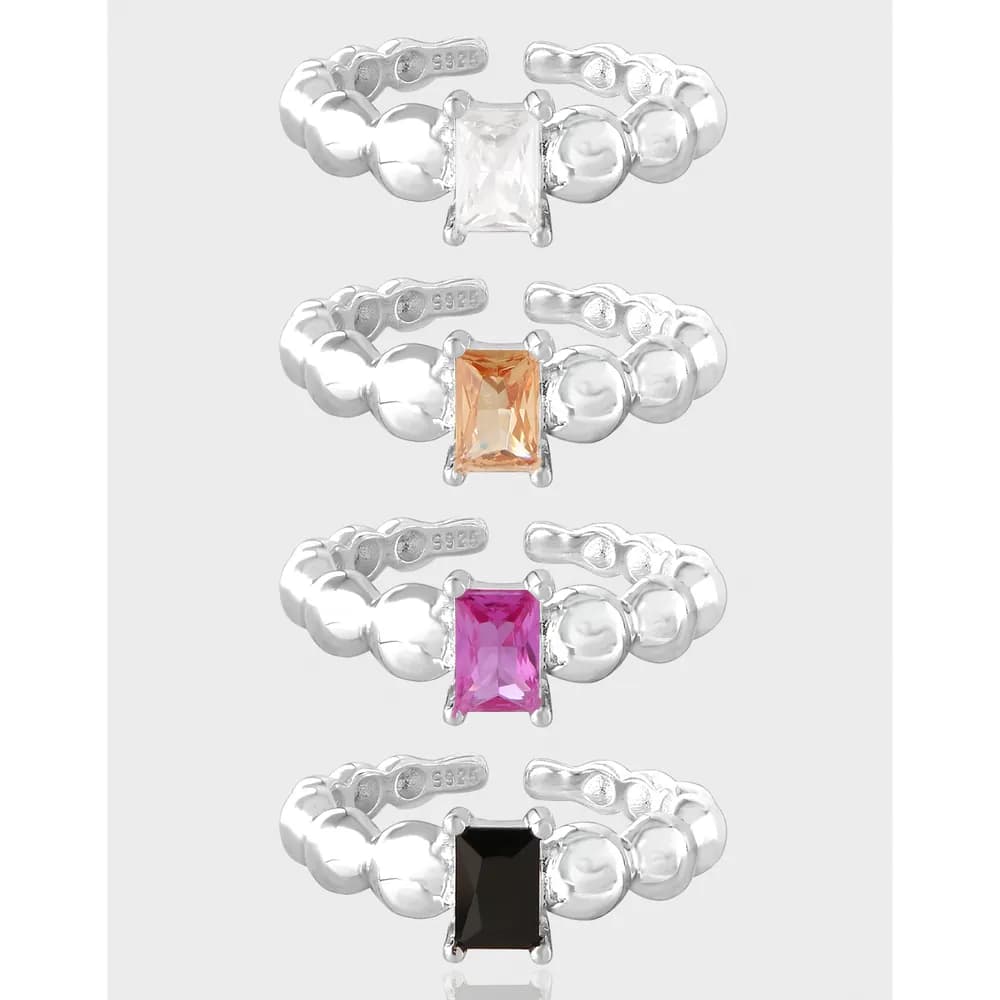 Four sterling silver bubble-band rings each with a rectangular princess-cut stone in different colors.