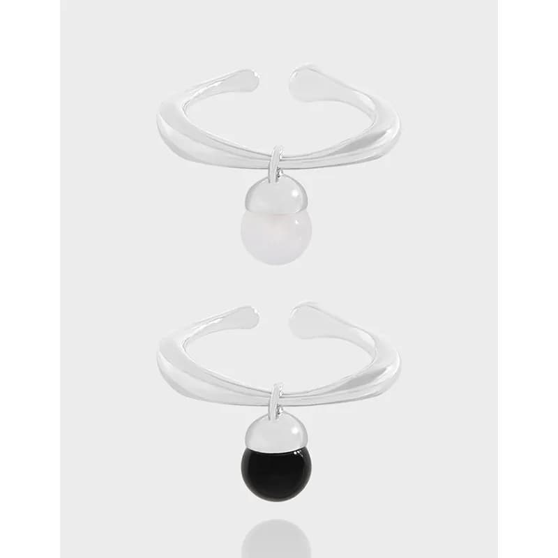 Open-cuff silver ring with a small pearl pendant hanging from a loop