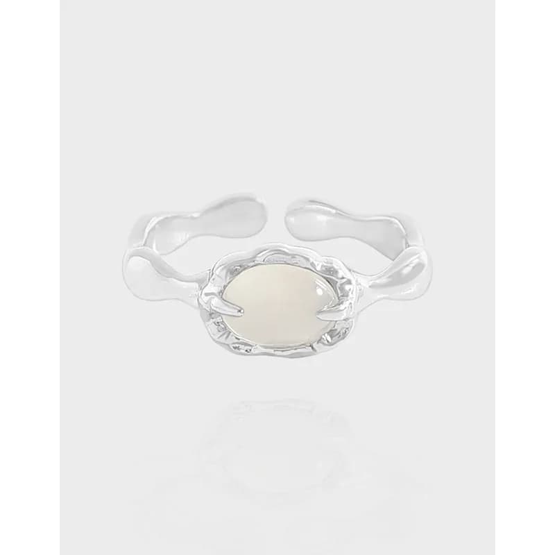 Polished sterling silver ring with an oval milky stone in a sculpted bezel and a wavy, organic band.