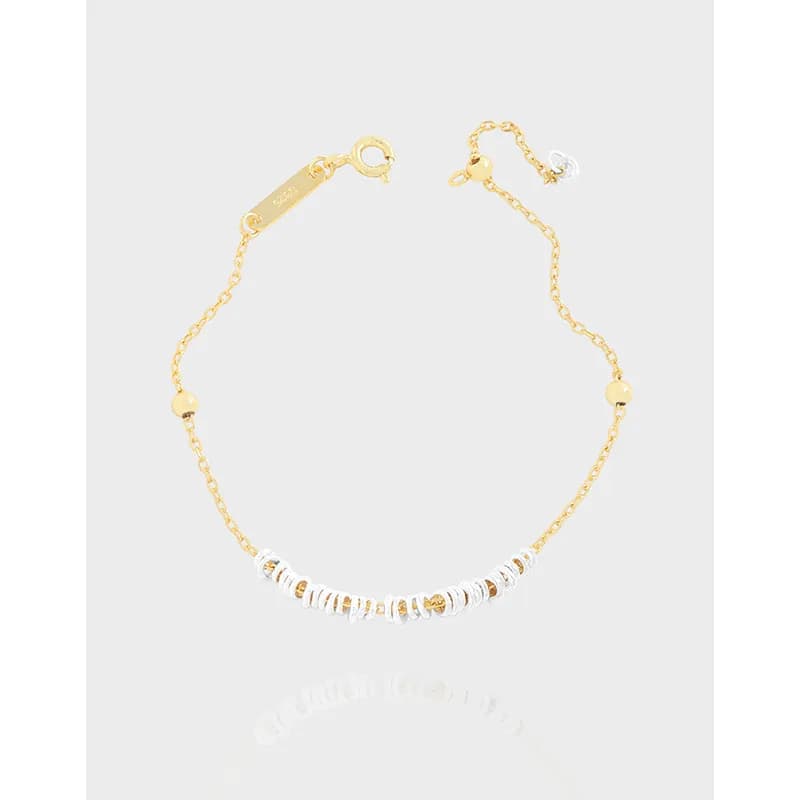 Delicate two-tone bracelet with a curved row of white beads and small gold accents on a fine chain.
