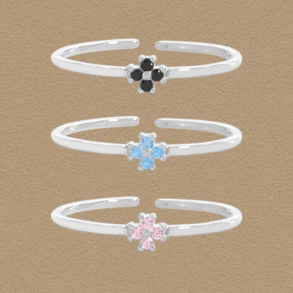 Three sterling silver open-band rings, each with a colored flower cluster centerpiece in black, blue, and pink tones.