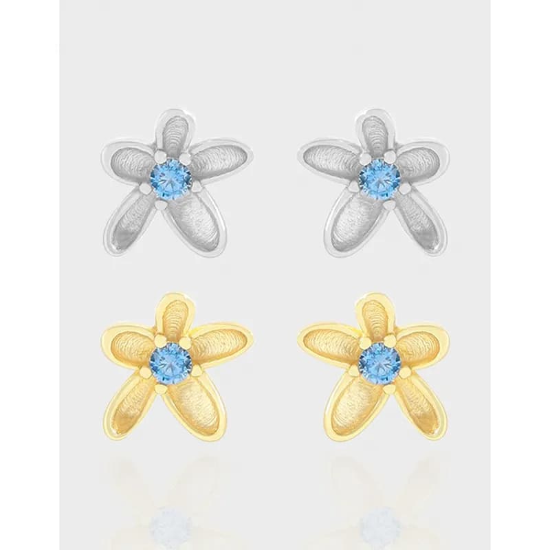 Flower-shaped stud earrings with blue center stones in silver and gold-tone finishes