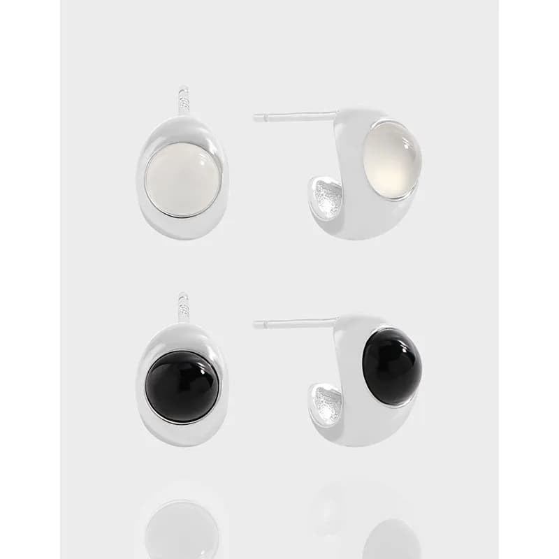 Polished sterling silver oval drop earrings with a domed cabochon center in white and black variants.