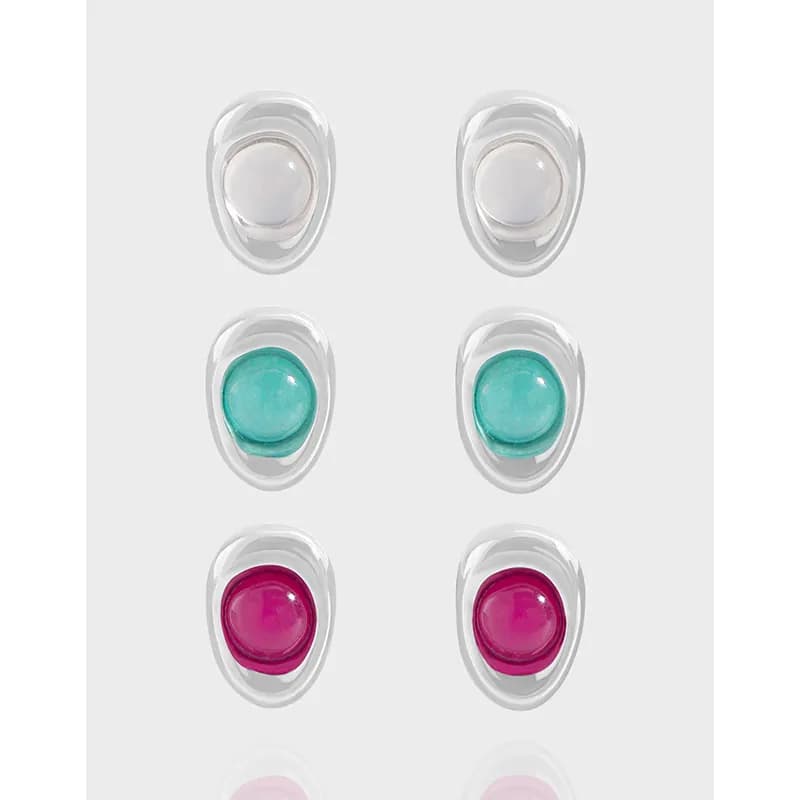 Two columns of oval sterling silver earrings with enamel cabochons in white, turquoise, and magenta seen from the front.