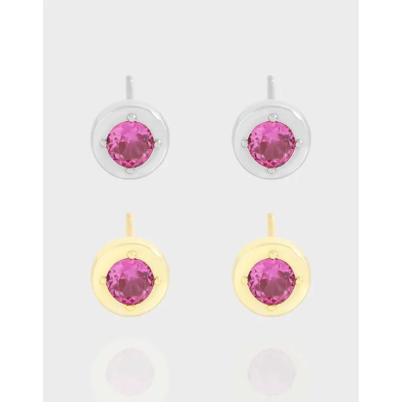 Pair of polished silver and gold-tone circular stud earrings with pink round gemstones.