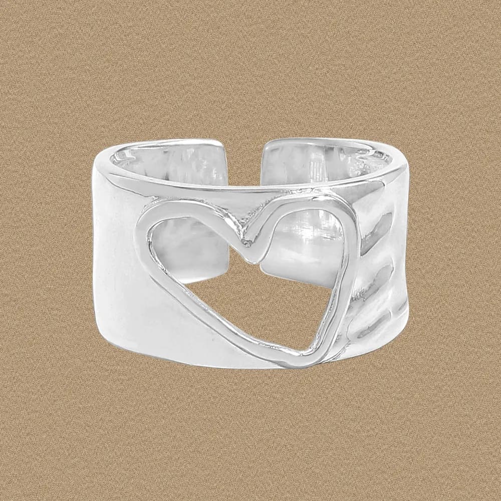 Wide polished sterling silver ring with a heart cutout on a warm beige background.