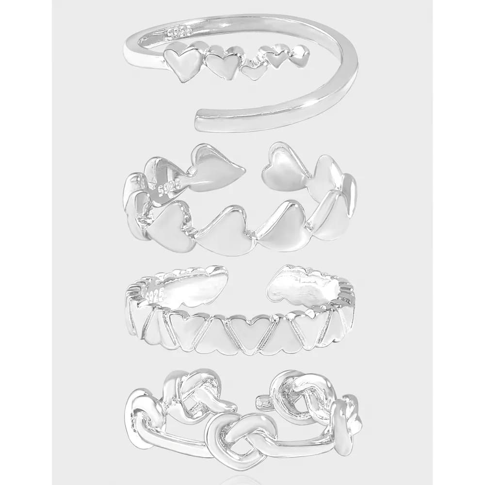 Collection of polished sterling silver rings with heart motifs displayed together against a light background.