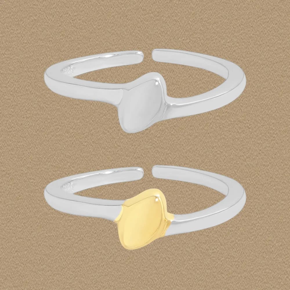 Two polished sterling silver rings with an open band and a smooth, rounded central motif, one with a gold-toned center accent.