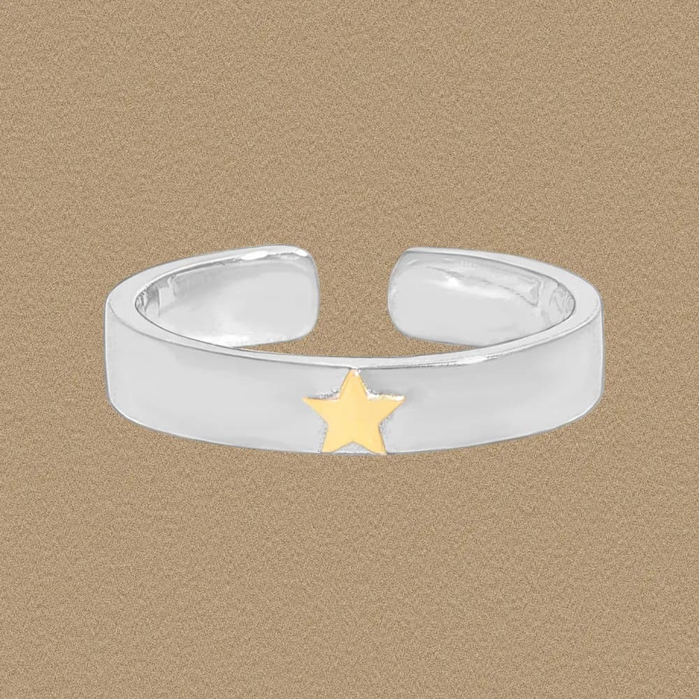Polished sterling silver ring with a small gold star accent on a neutral backdrop.