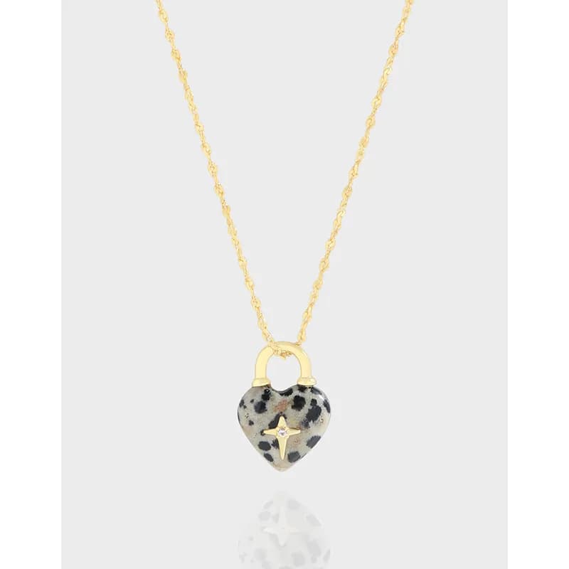 Delicate necklace with a speckled heart pendant hanging centered against a light background.