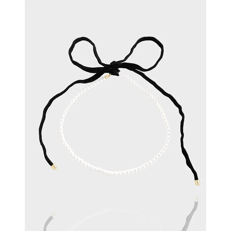Delicate pearl bead necklace with a black ribbon tie and bow at the back.