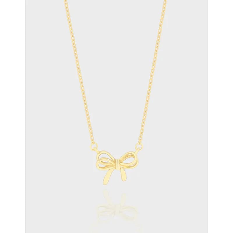 Close-up of a polished bow pendant on a fine chain necklace