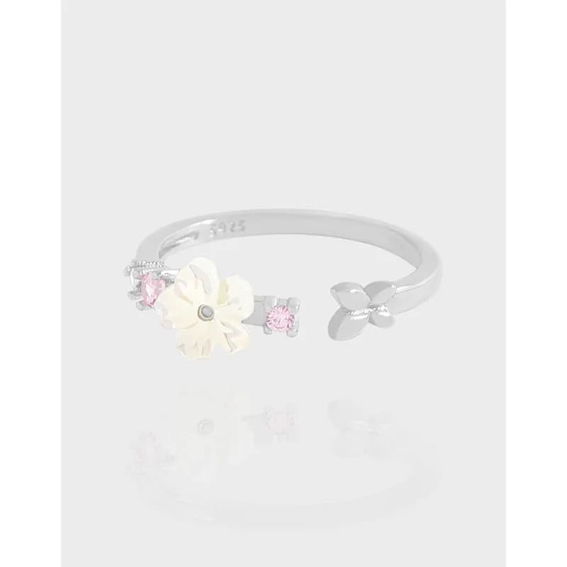 Sterling silver floral ring with cream enamel flower and pink stones on an open band.