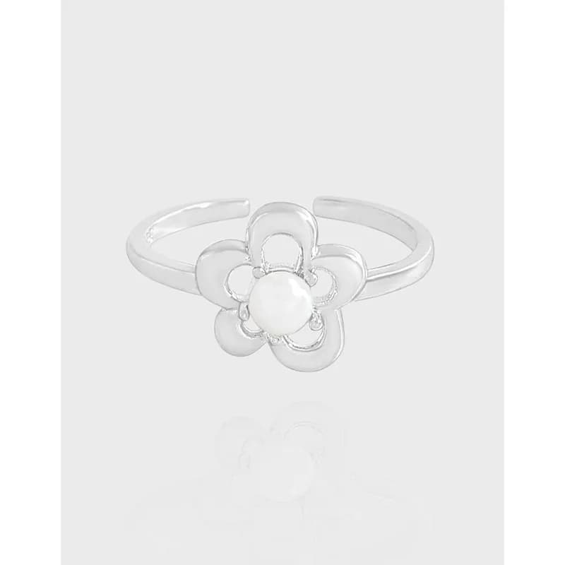 Polished silver flower ring with a central pearl sits on a slim band.