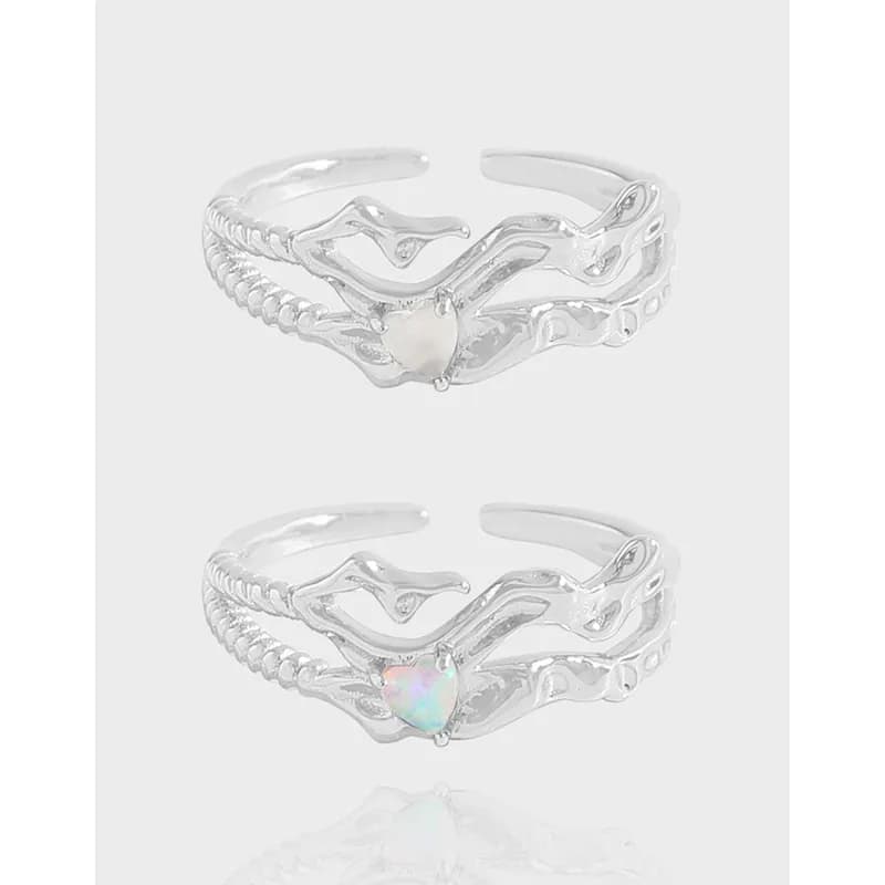 Polished sterling silver ring with a heart-shaped iridescent stone centerpiece on an open sculptural band.