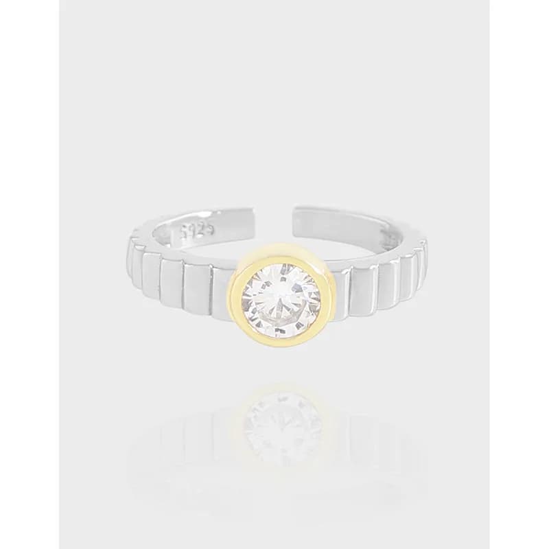 Polished sterling silver ring with a round stone set in a gold bezel at the center.
