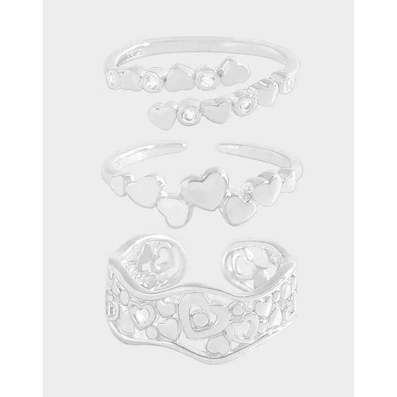 Close-up of a stackable sterling silver ring with heart shapes and filigree detailing.