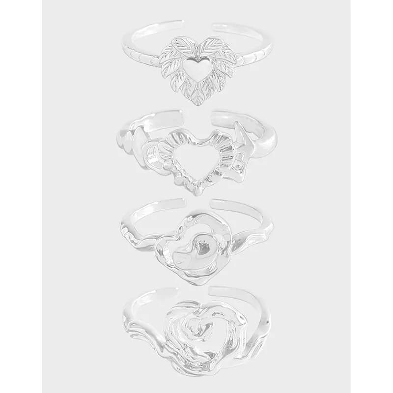 Four polished sterling silver rings with heart motifs arranged in a vertical stack on a light background.